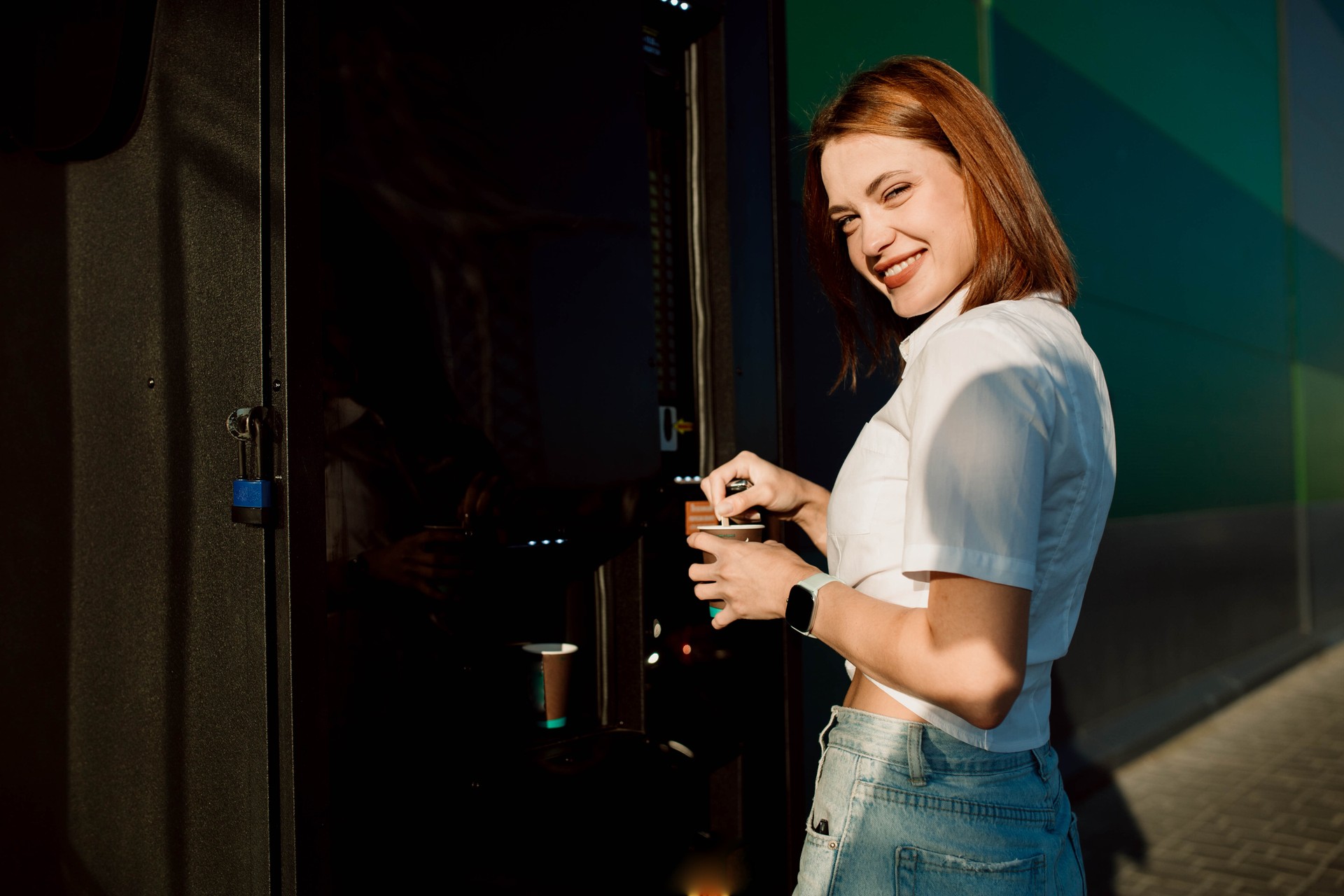 beautiful woman buying coffee from a coffee machine in a shopping center